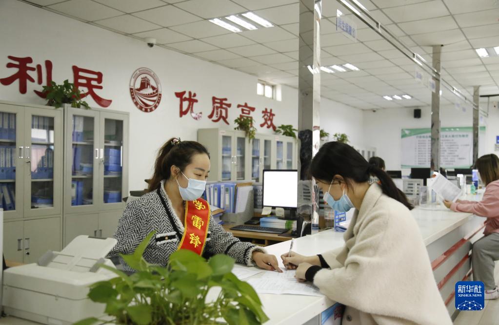 河北省邢臺市襄都區宴家屯鎮綜合服務中心工作人員協助辦事群眾填寫相關表格（2022年3月30日攝）。