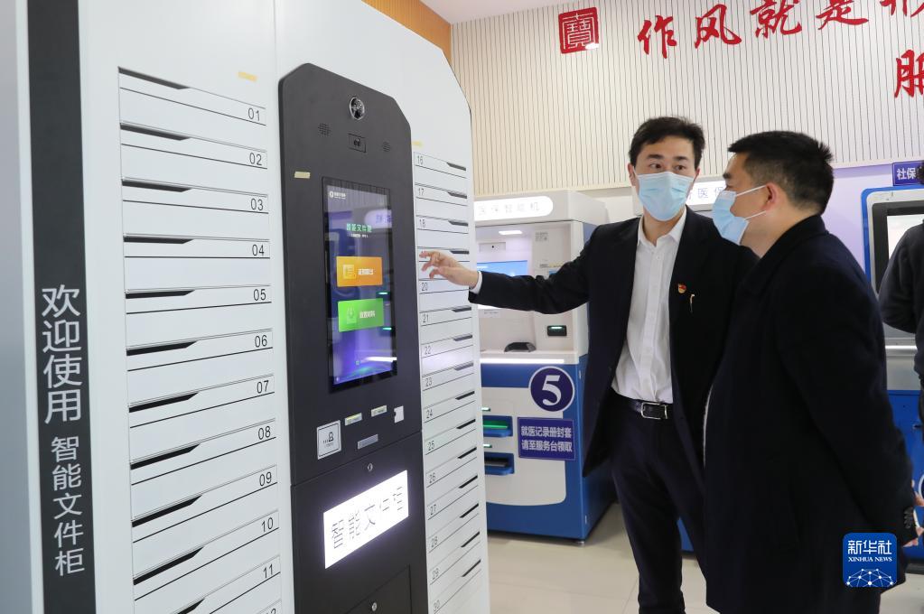 上海市閔行區七寶鎮社區事務受理服務中心的工作人員（左）向前來辦事的居民介紹智能文件柜的使用方法（2021年3月3日攝）。